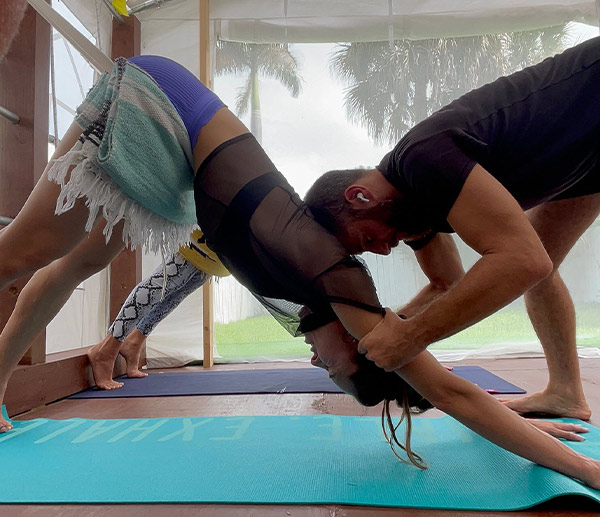 man helping a woman in a yoga class